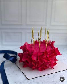 a cake that has been decorated with red flowers and gold stems on top of it