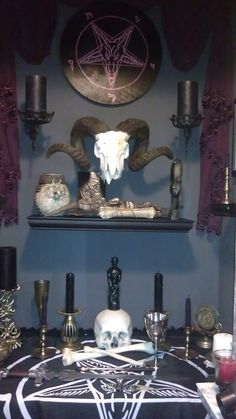 a table topped with skulls and candles in front of a wall mounted wiccah