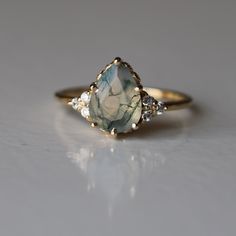 a close up of a ring with a stone in the middle and three diamonds around it