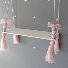 a shelf with pink tassels hanging from it's sides and stars on the wall