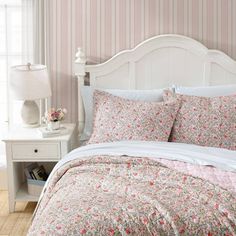 a bed with pink and white flowers on it in a bedroom next to a window