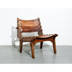 a wooden chair sitting on top of a cement floor in front of a white wall