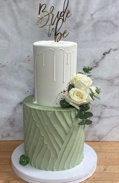 a green and white wedding cake with flowers on top