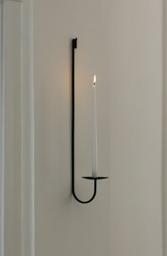 a candle that is on the wall next to a light fixture with a black handle