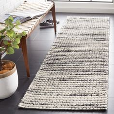 a white rug is on the floor next to a potted plant in front of a window