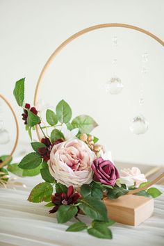 a bouquet of flowers sitting on top of a wooden block next to a circular mirror