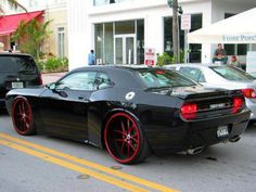 a black sports car with red rims parked on the street