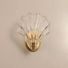 a glass scallop is mounted on a gold - plated metal wall light