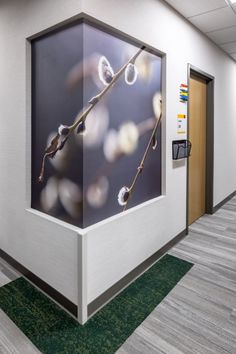 an office hallway with a painting on the wall and green carpeted flooring in front of it