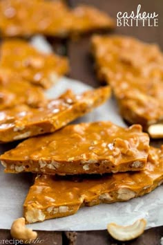 pieces of peanut butter brittle on top of parchment paper with cashews in the background