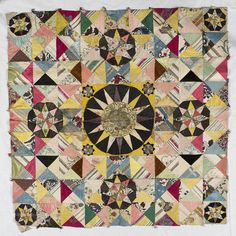 an old quilt that has been made into a wall hanging or table topper with many different colors and shapes