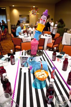 a dining room filled with tables covered in white and black striped table cloths, colorful objects on top of them