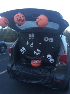 the back end of a car with halloween decorations on it and pumpkins in the trunk