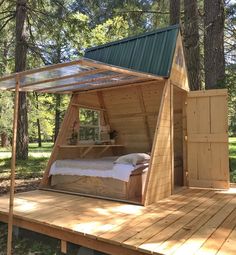 a bed in the shape of a tent on a wooden platform with a green roof