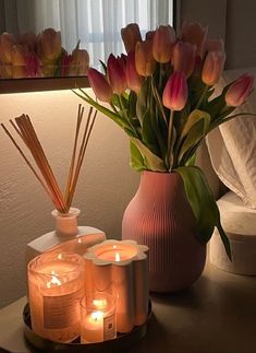 candles and flowers on a table in front of a mirror with a vase full of tulips