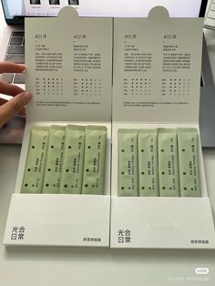 two rows of green tea packets in front of a laptop