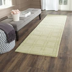 a living room with wood flooring and white rugs on the floor next to a gray couch