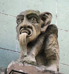 a gargoyle on the side of a building with its mouth open and tongue out