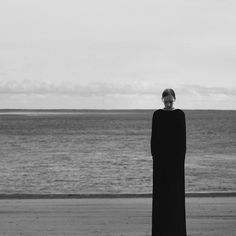 a woman standing on the beach next to the ocean