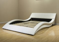 a bed that is sitting on top of a hard wood floor in a room with white walls