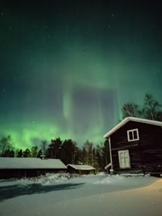 an image of the aurora bore in the sky over a barn and trees with snow on it