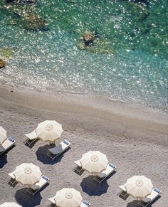 beach chairs and umbrellas are lined up on the sand near the water's edge