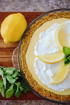 a pie with lemons and whipped cream on top next to some minty leaves