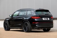 the rear end of a black suv parked in front of a building