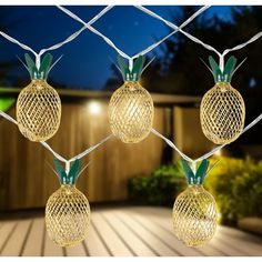 three pineapple lights hanging from a chain link fence