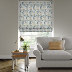 a living room scene with focus on the couch and window blinds that have blue flowers