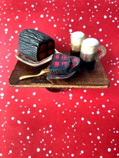 a wooden tray topped with different items on top of a red table covered in snow