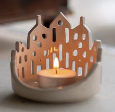 a lit candle sits on a table in front of a house ornament that is shaped like a castle