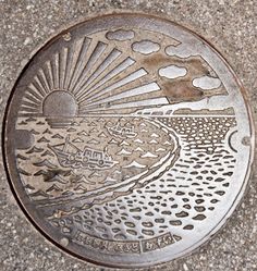 a manhole cover on the ground with an image of a sun and clouds above it