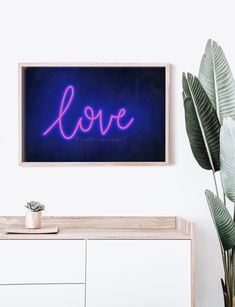 a blue neon sign that says love on the wall next to a potted plant