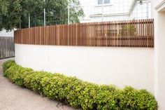 a white wall with wooden slats on the top and bottom, next to a sidewalk