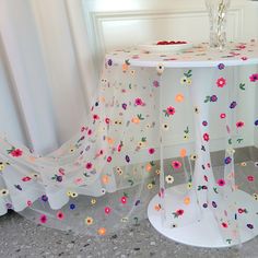 a white table with flowers on it next to a vase