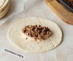 an uncooked tortilla with ground meat on top