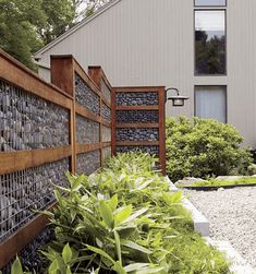 an image of a garden fence in front of a house with text overlay that reads diy gabion fence rock walls without concrete