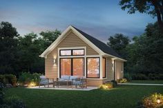 a small house is lit up at night with lights on the porch and patio area