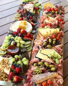 an assortment of cheeses, fruits and meats laid out on a wooden table