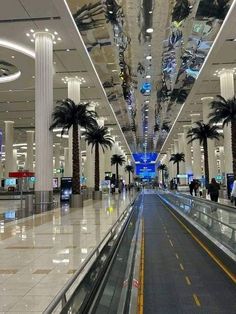 the inside of an airport with palm trees and lights hanging from it's ceiling