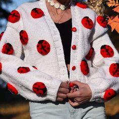 a ladybug sweater with red and black spots on the sleeves is worn by a woman