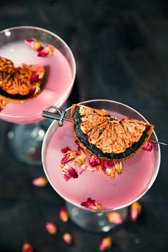 two desserts with orange slices and flowers in them on pink plates next to each other