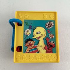 a yellow children's toy with sesame characters on it