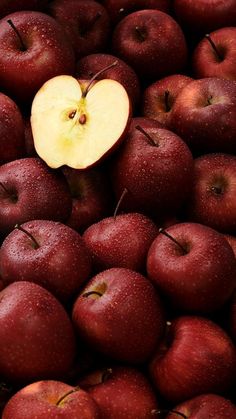 a pile of red apples with one apple cut in half