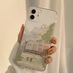 a woman holding up a phone case with an image of a farm scene on it