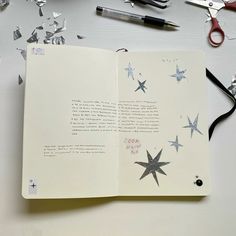 an open book with scissors and paper stars on it