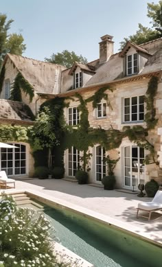 a house with a pool in front of it and lots of greenery on the walls