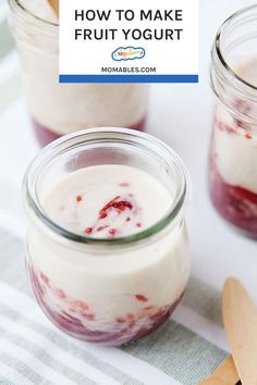 two jars filled with yogurt sitting on top of a table next to wooden spoons