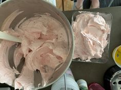 two pans filled with pink frosting on top of a table